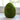 An artificial mossy egg decoration placed on a table, predominantly green in color.