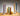 Various Greentree brand candles in holders, lit.