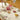 Decorative table setting with floral tablecloth, fruit plates, and teapot on a yellow background