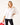 Woman wearing a white blouse and black pants holding a red handbag on a white background
