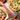 Image shows a pizza cut into six pieces with the soft-grip rocking pizza cutter underneath. There is another uncut pizza in the bottom left corner.