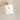 Hand holding a plantable seed paper envelope with illustrations on a beige background