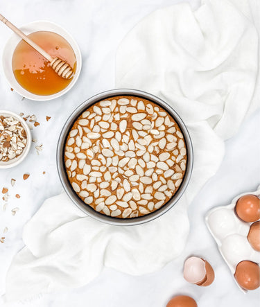 8 Inch Round Cake Pan With cake inside, image features bowl of honey, bowl of almond slices and eggs