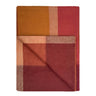 Plaid blanket with a pattern of red, orange, and brown on a white background