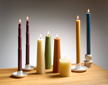 Various Greentree brand candles in holders, lit.