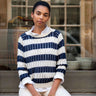 Woman wearing a blue and white striped sweater sitting in front of a window.