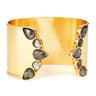 A wide gold cuff bracelet decorated with a series of teardrop-shaped and round dark gray labradorite stones on each side, shown against a plain white background.