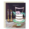 Congratulations card featuring drawn image of three layer cake adorned with flowers and bunting. It sits on a mint green cake plate, and there are two candlesticks with candles lit in the background.
