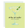 A Tini Bit Older. Happy Birthday — a fun birthday card featuring a beautifully drawn martini with two olives on a cocktail pick.