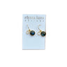 A pair of gold hoop earrings with round dark blue-green labradorite stones, displayed on a white card labeled 'elyssa bass DESIGNS' against a red brick background.